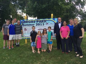 Friends of Gorgas Park, and park volunteers from City Light Church join East River Bank President Christopher McGill and employees and volunteers from the bank in front of the 2015 Concert and Movie Series Sign.